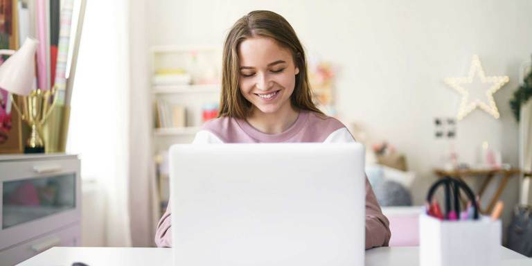een glimlachende persoon achter een computer