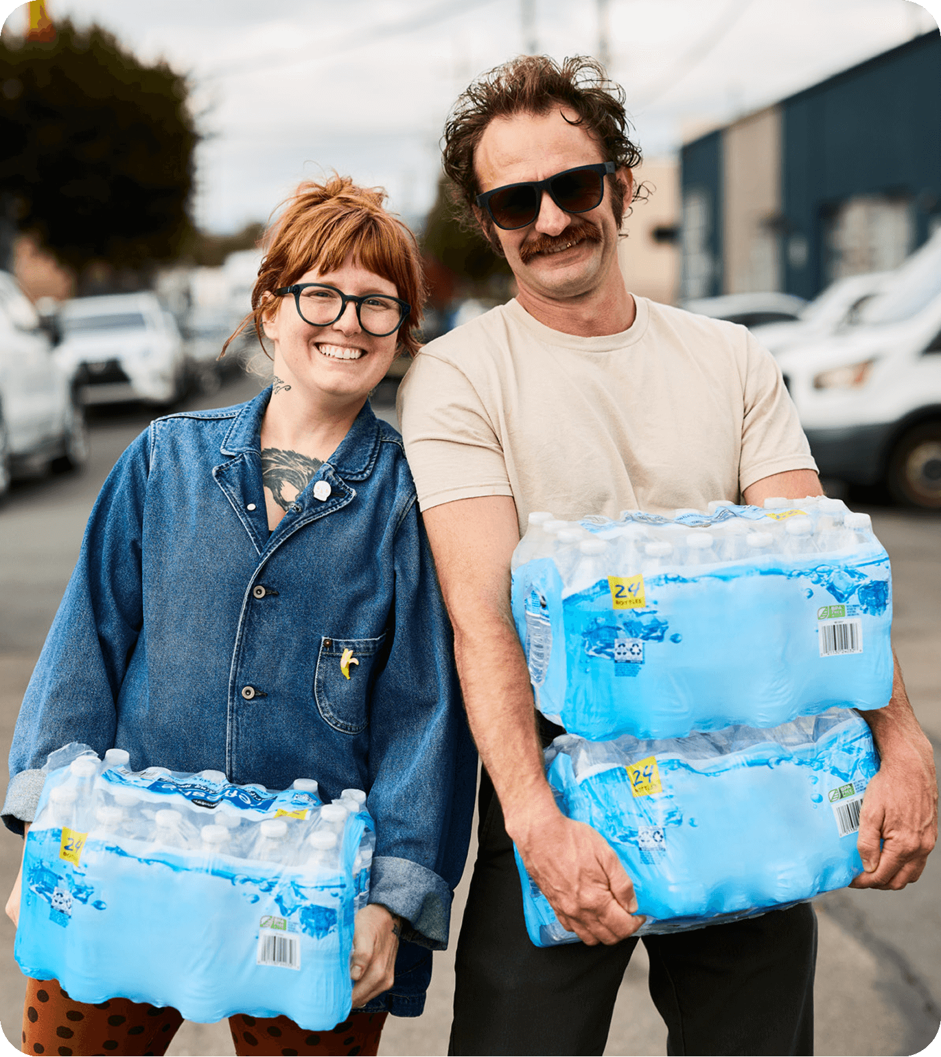 Two people smiling while holding cases of bottled water